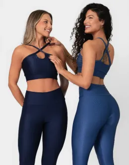 Duas modelos utilizando conjunto de legging com top de alças cruzadas, em tecido brilhante na cor azul-marinho